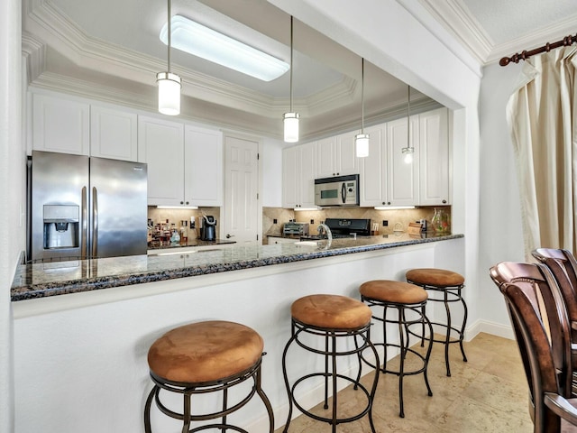 kitchen with appliances with stainless steel finishes, backsplash, white cabinetry, and dark stone counters