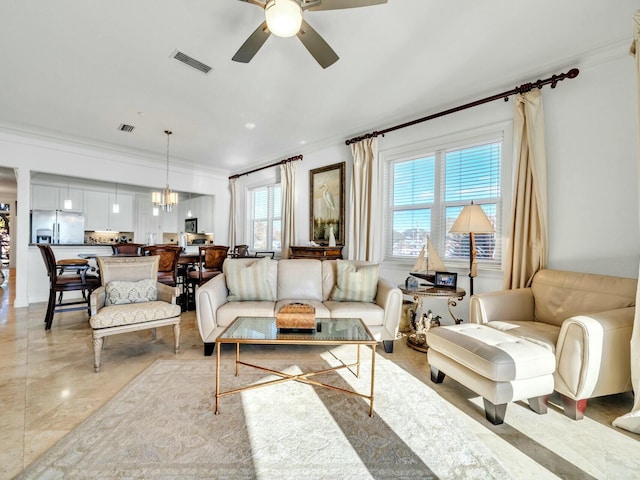 living room featuring ceiling fan with notable chandelier and crown molding