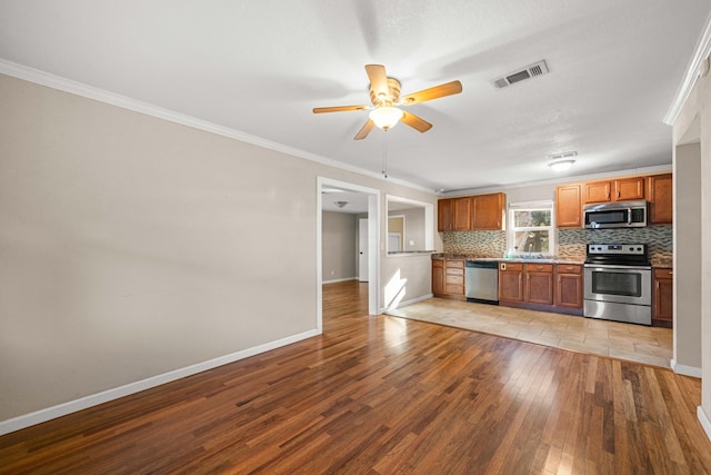 kitchen with light hardwood / wood-style flooring, ornamental molding, stainless steel appliances, and tasteful backsplash