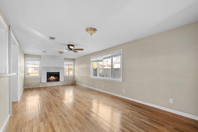 unfurnished living room with ceiling fan, light hardwood / wood-style floors, and a fireplace