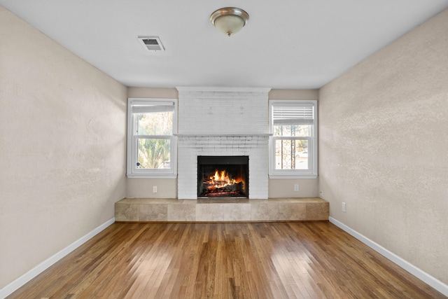 unfurnished living room with hardwood / wood-style floors, a fireplace, and a wealth of natural light