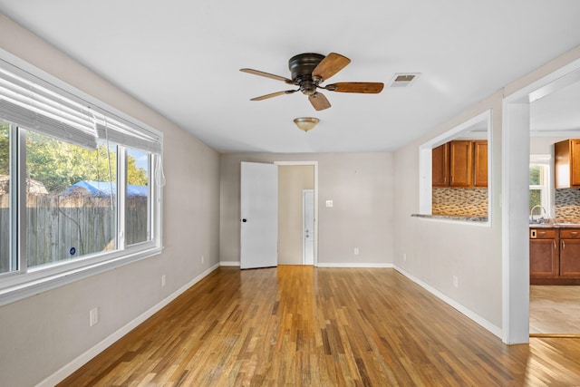 unfurnished room featuring ceiling fan, sink, and wood-type flooring