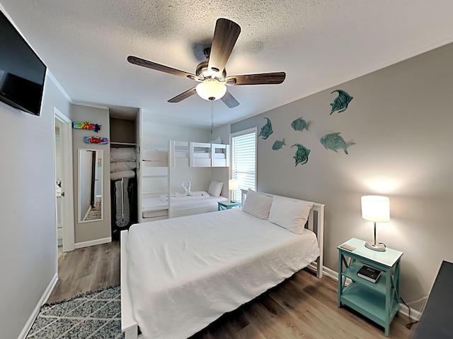 bedroom with a textured ceiling, ceiling fan, and hardwood / wood-style flooring