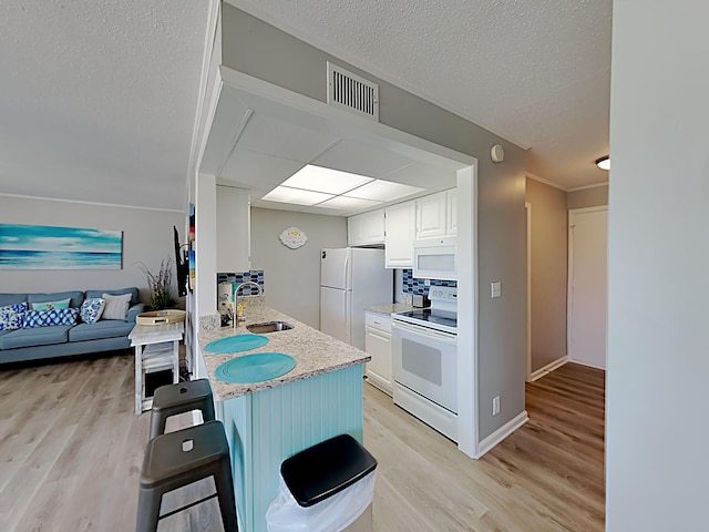 kitchen featuring white appliances, light hardwood / wood-style flooring, white cabinets, and a breakfast bar area