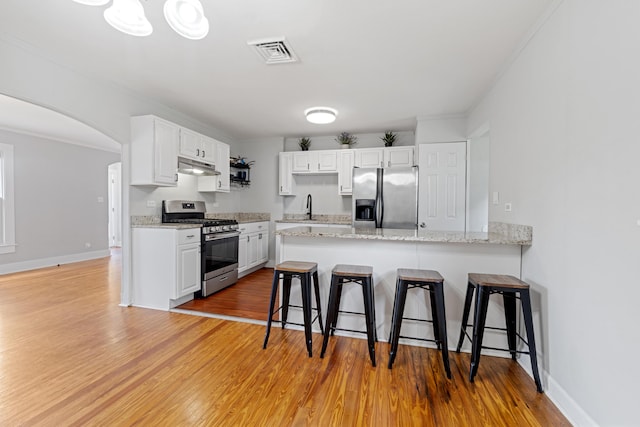 kitchen with sink, stainless steel appliances, kitchen peninsula, a breakfast bar area, and white cabinets