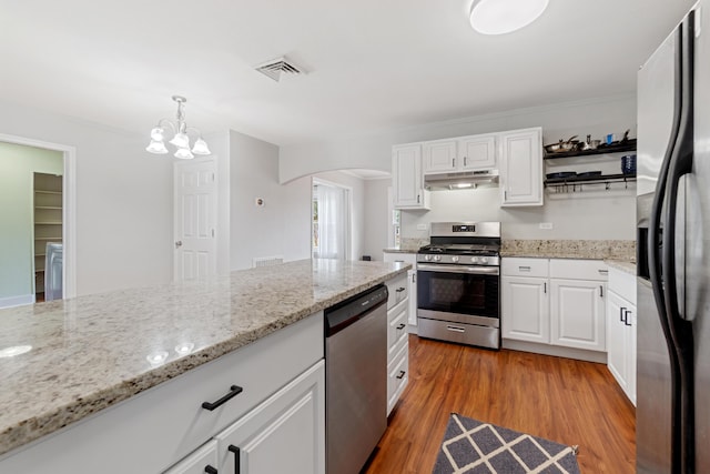 kitchen with pendant lighting, white cabinets, hardwood / wood-style flooring, light stone countertops, and stainless steel appliances