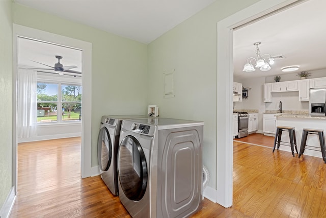 washroom with washing machine and dryer, sink, light hardwood / wood-style floors, and ceiling fan with notable chandelier