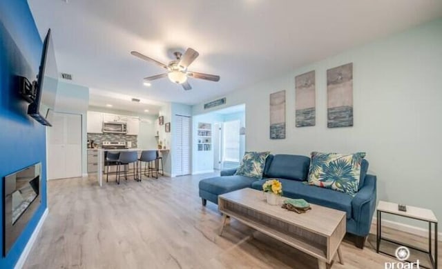 living room with ceiling fan and light hardwood / wood-style floors