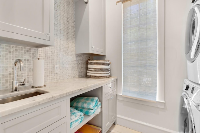 laundry room with cabinets, stacked washer / dryer, and sink