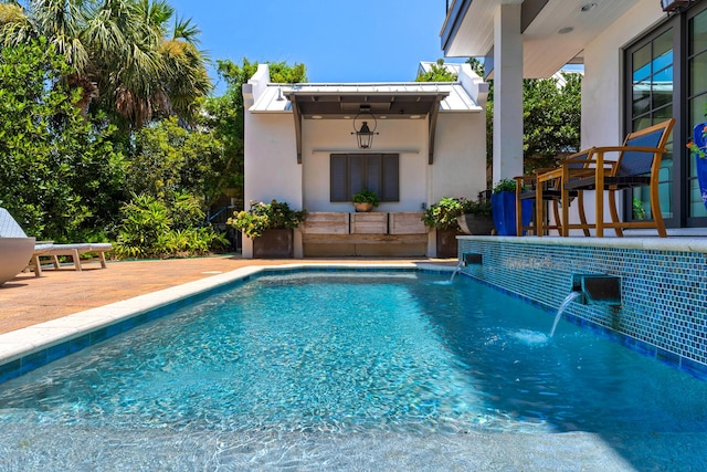 view of swimming pool with pool water feature and a patio