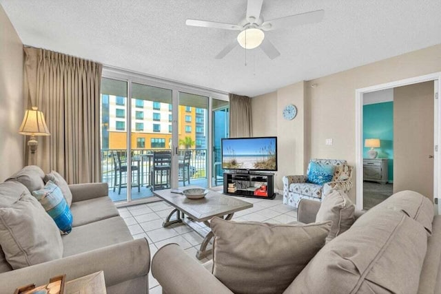 living room featuring ceiling fan, expansive windows, light tile patterned flooring, and a textured ceiling