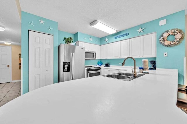 kitchen featuring white cabinets, sink, a textured ceiling, appliances with stainless steel finishes, and kitchen peninsula