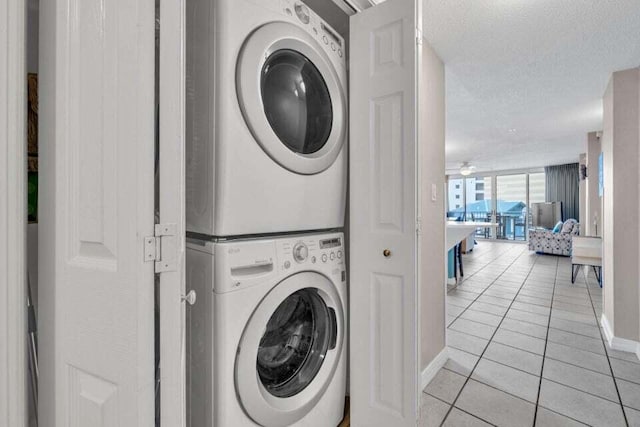 laundry area featuring light tile patterned floors, a textured ceiling, and stacked washer / dryer