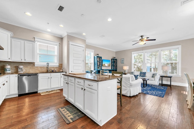 kitchen featuring stainless steel dishwasher, a kitchen breakfast bar, dark hardwood / wood-style flooring, a kitchen island, and white cabinets