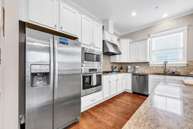 kitchen with white cabinetry, tasteful backsplash, ornamental molding, appliances with stainless steel finishes, and light stone countertops