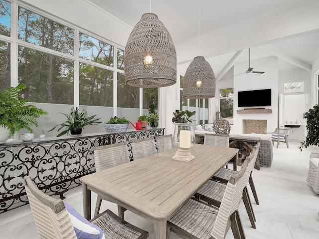 dining space with beamed ceiling, ceiling fan, a fireplace, and high vaulted ceiling