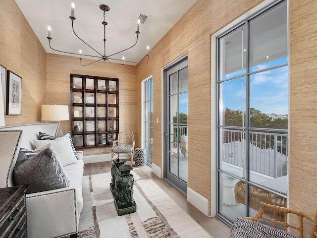 sitting room with a chandelier, light wood-type flooring, and expansive windows