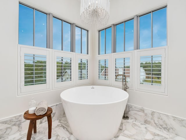 bathroom featuring plenty of natural light, a tub, a high ceiling, and an inviting chandelier