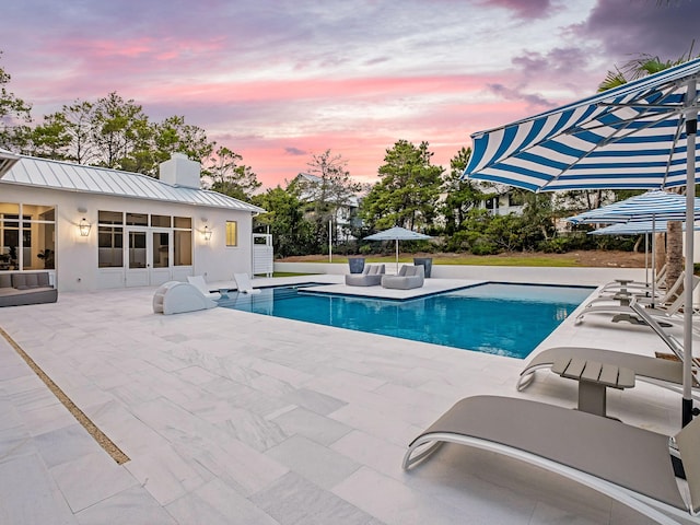 pool at dusk featuring a patio