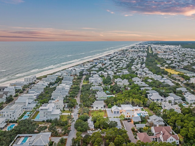 aerial view at dusk with a water view and a beach view