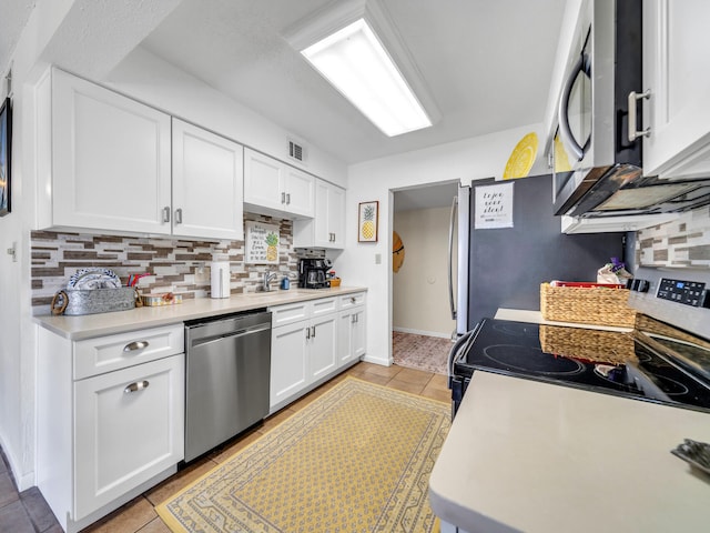 kitchen with backsplash, white cabinets, sink, light tile patterned floors, and appliances with stainless steel finishes