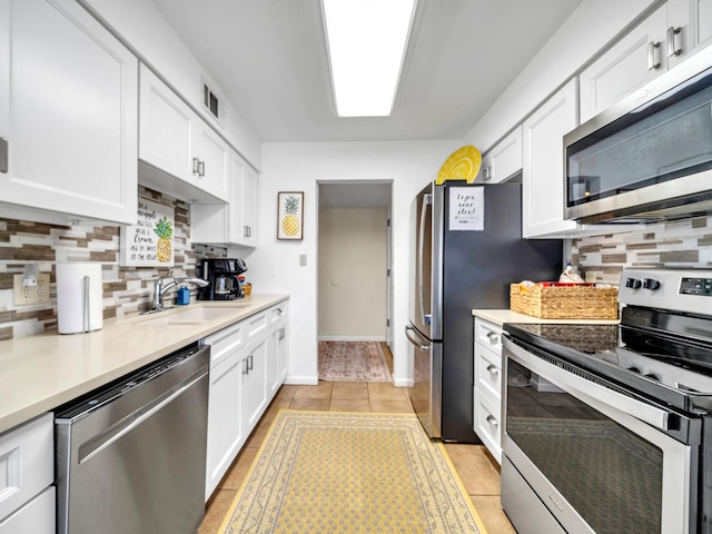 kitchen with white cabinets, appliances with stainless steel finishes, light tile patterned flooring, and sink