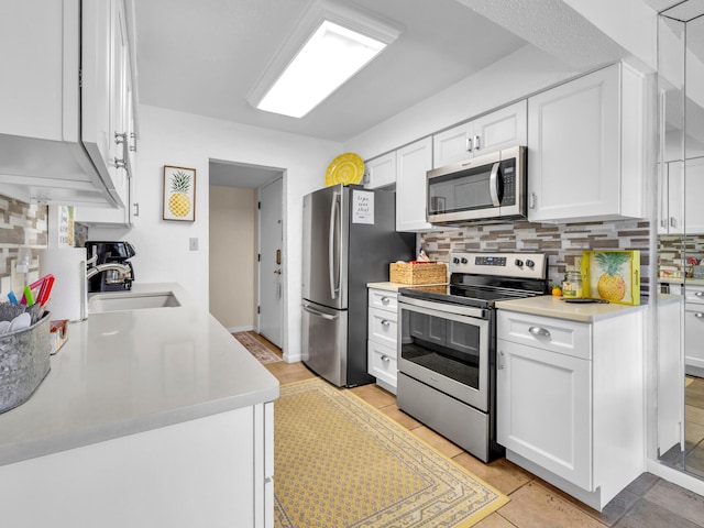 kitchen with light tile patterned flooring, sink, white cabinets, and stainless steel appliances