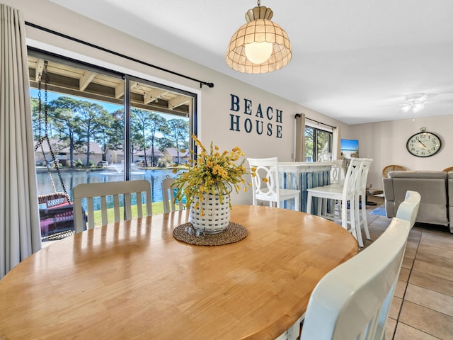 dining area with ceiling fan, a water view, and light tile patterned floors