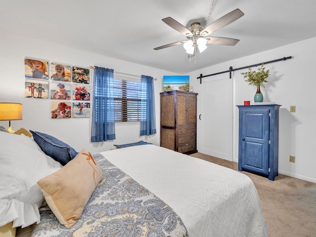 carpeted bedroom featuring ceiling fan and a barn door