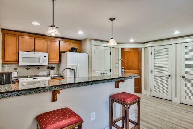 kitchen featuring white appliances, pendant lighting, and a kitchen breakfast bar