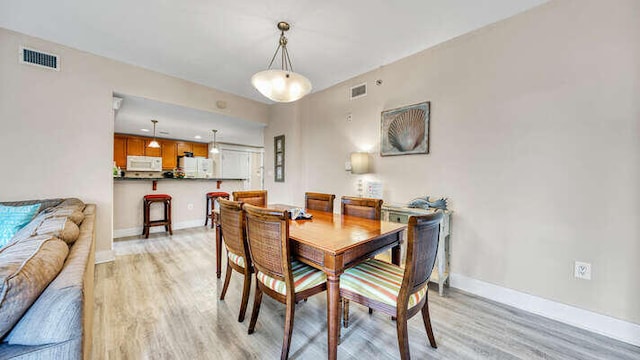 dining space with visible vents, light wood finished floors, and baseboards