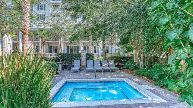 view of swimming pool featuring a patio area, fence, and a hot tub