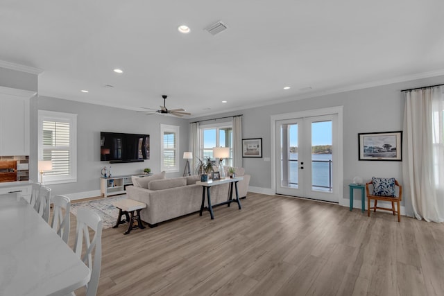 living area with visible vents, light wood finished floors, a healthy amount of sunlight, and french doors