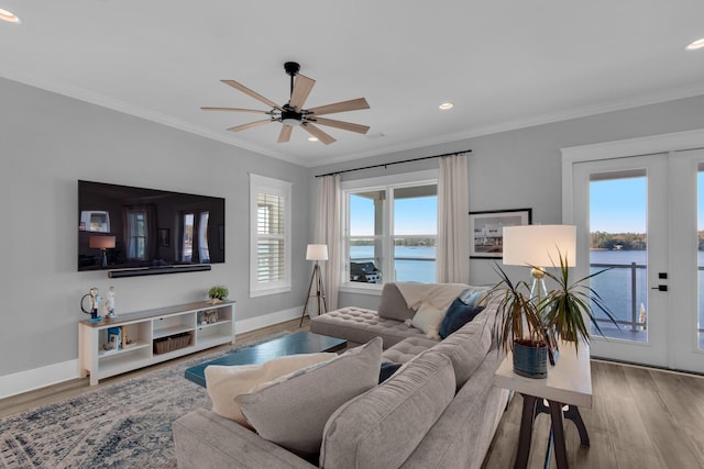 living area featuring wood finished floors, a water view, and ornamental molding