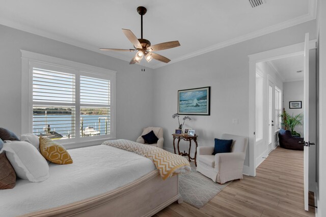 bedroom featuring light wood-style floors, ornamental molding, and a ceiling fan