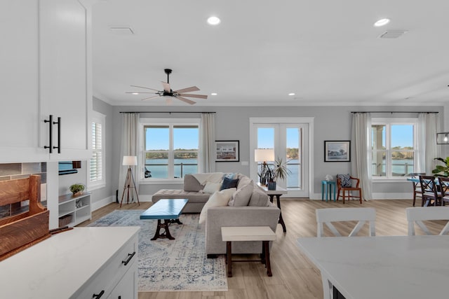 living area featuring visible vents, baseboards, ornamental molding, recessed lighting, and light wood-style floors