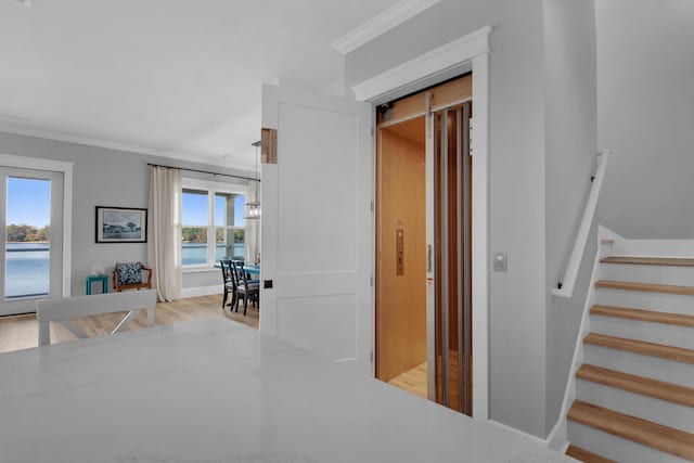 hall featuring baseboards, light wood-style flooring, stairs, and crown molding