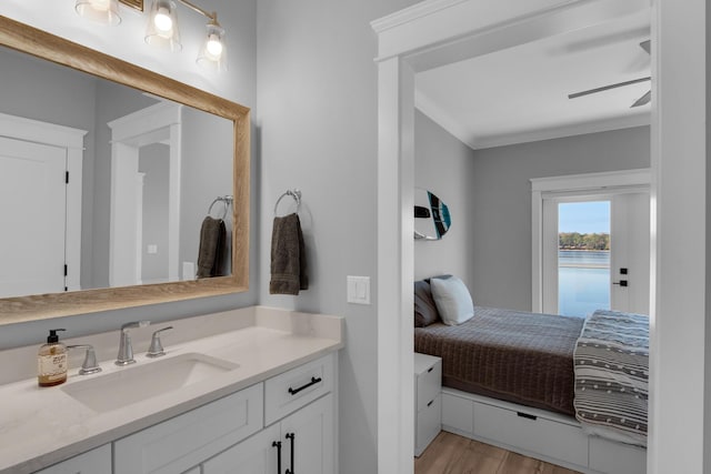 bathroom featuring a water view, ornamental molding, a ceiling fan, wood finished floors, and vanity