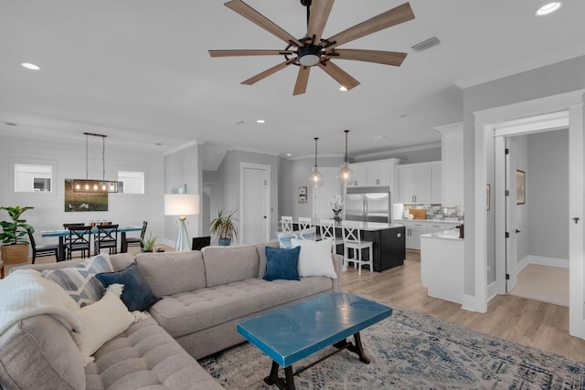 living area featuring visible vents, recessed lighting, light wood-style floors, and ornamental molding