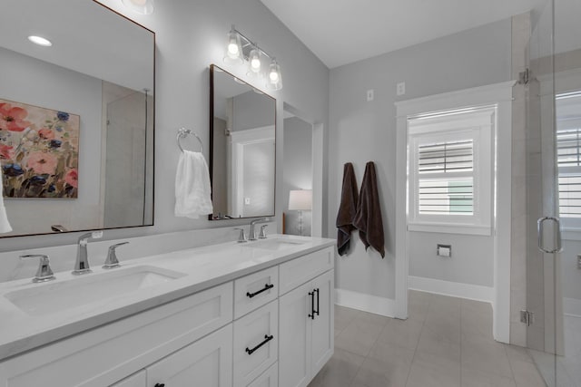 full bath with double vanity, a shower stall, baseboards, and a sink