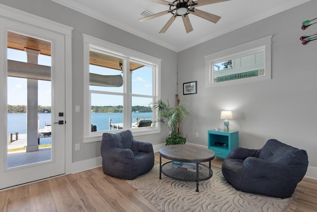 sitting room featuring wood finished floors, baseboards, ceiling fan, ornamental molding, and a water view