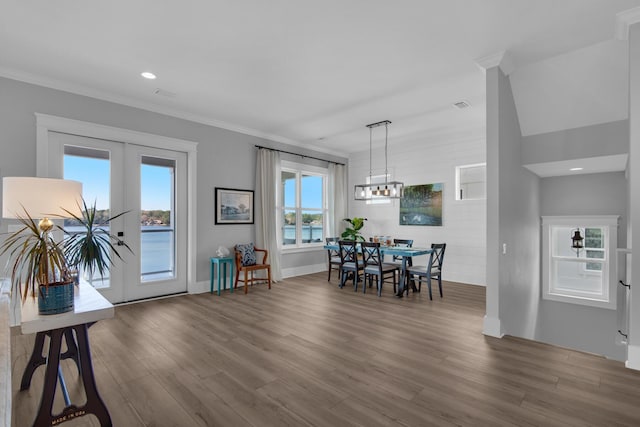 dining space with french doors, crown molding, and wood finished floors