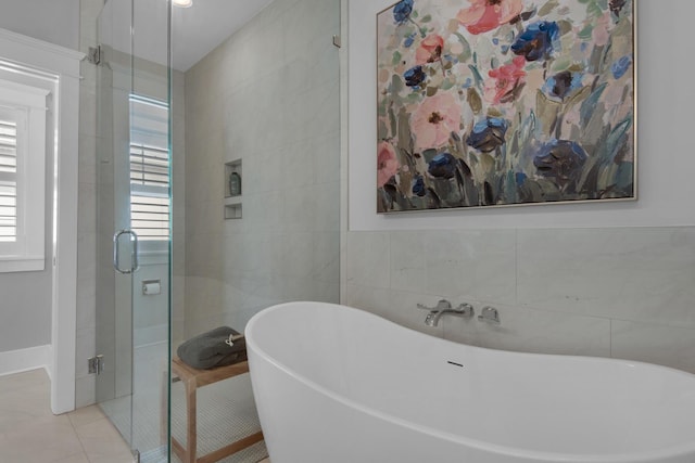 bathroom featuring tile walls, tile patterned floors, a shower stall, and a freestanding bath