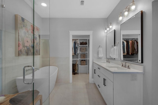 full bath featuring visible vents, a freestanding tub, a walk in closet, and a sink