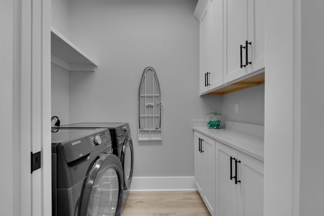 laundry room featuring washer and dryer, baseboards, cabinet space, and light wood finished floors