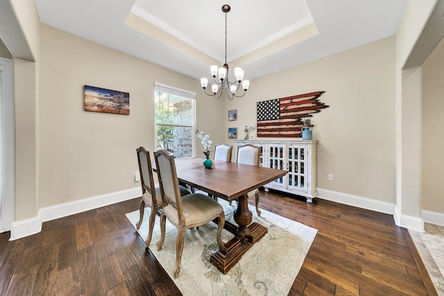 dining area featuring a notable chandelier, dark hardwood / wood-style floors, and a raised ceiling