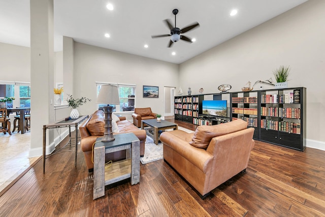 living room with ceiling fan, a high ceiling, and dark hardwood / wood-style floors