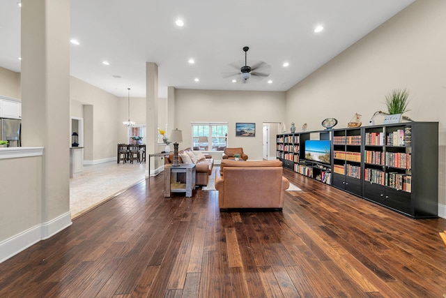 living room featuring a towering ceiling, dark hardwood / wood-style flooring, and ceiling fan with notable chandelier