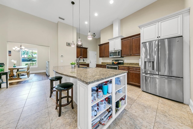 kitchen featuring a breakfast bar, appliances with stainless steel finishes, decorative light fixtures, and sink