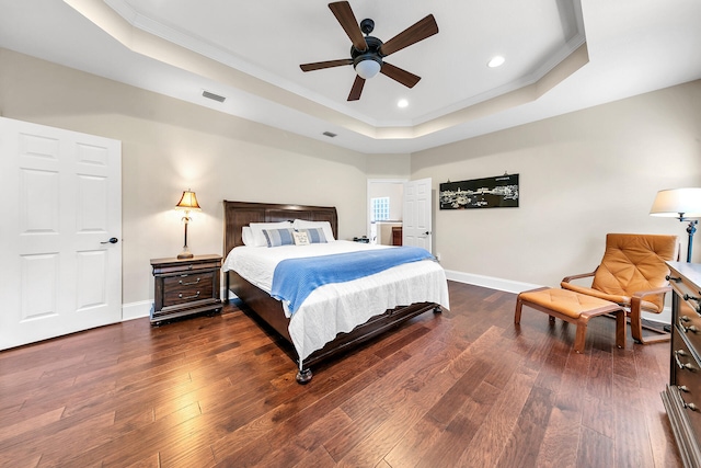 bedroom with ceiling fan, crown molding, dark wood-type flooring, and a tray ceiling